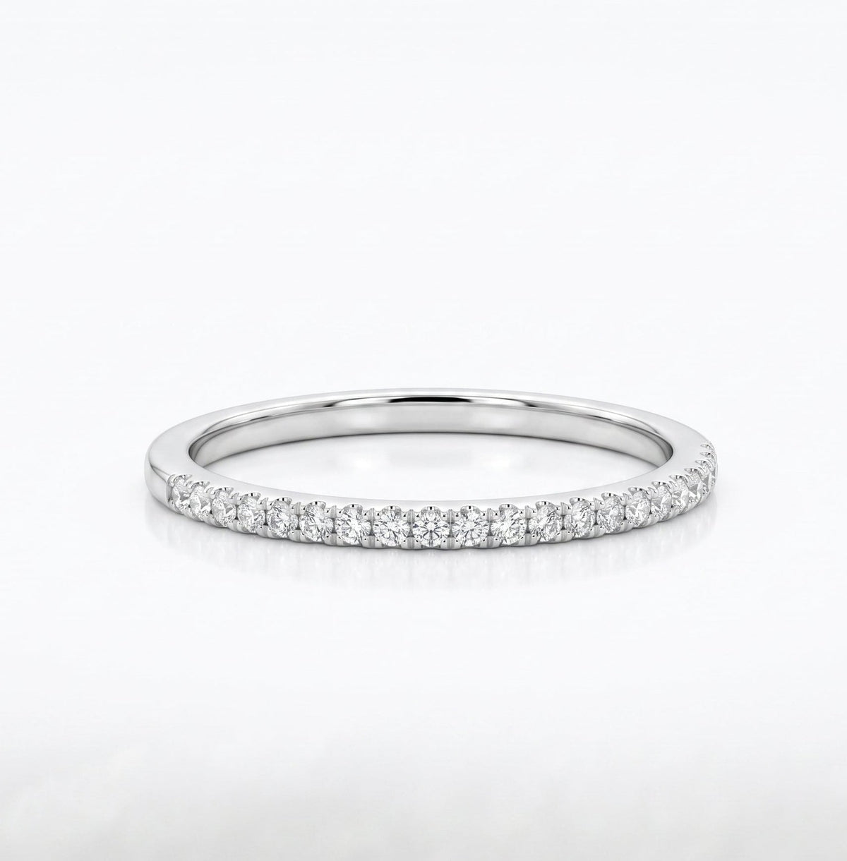 A thin silver band ring set with a row of small clear gemstones along the outer edge, photographed on a clean white background.