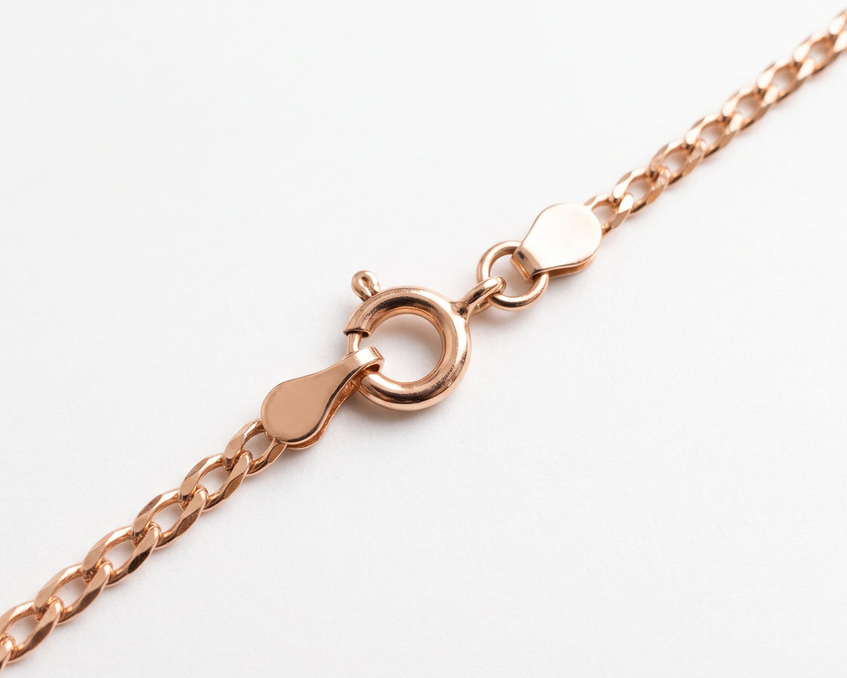 Close-up of a silver gold plated chain necklace with a lobster clasp and heart-shaped tag, shown on a clean white background.
