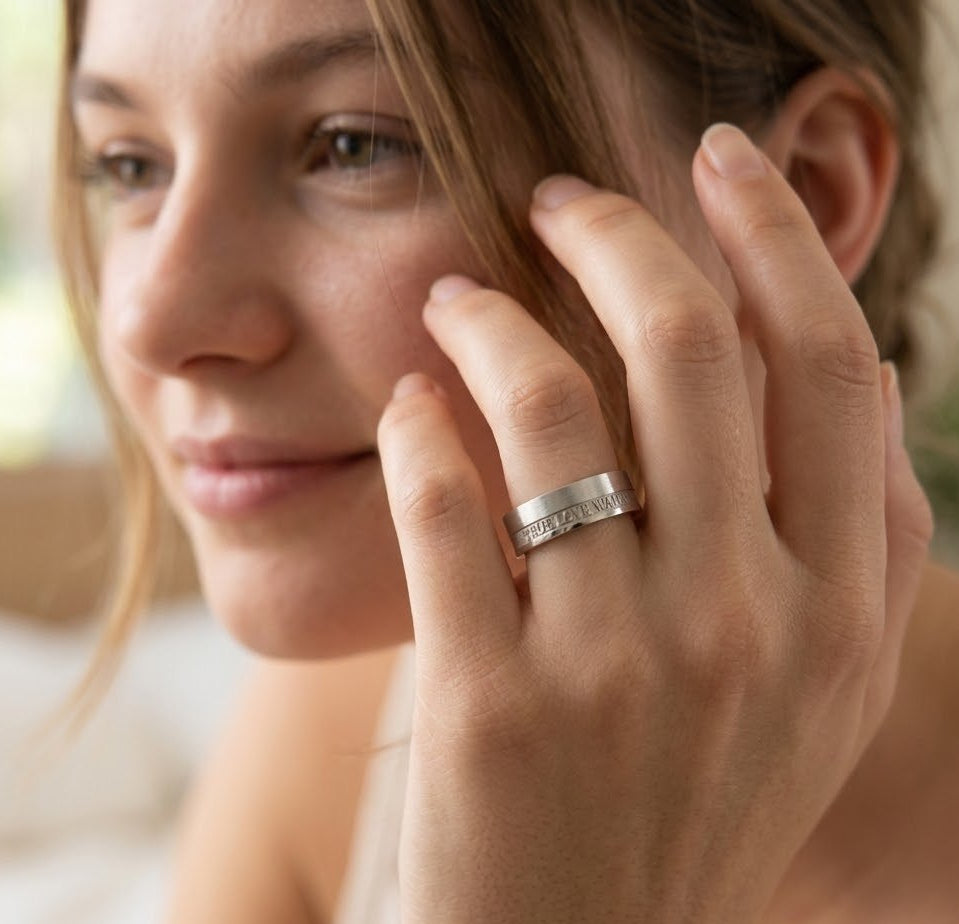 Close-up of a woman's hand with a silver ring on her finger, touching her face.