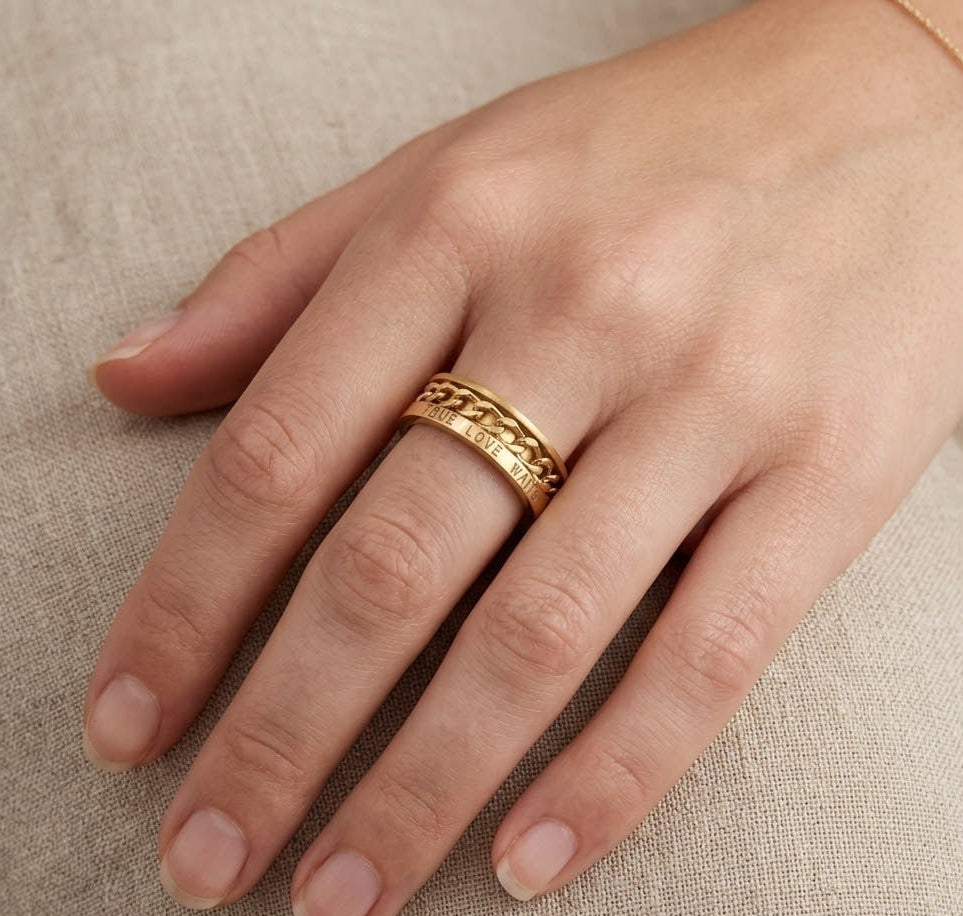 Gold-plated silver chain ring on a hand against a beige fabric background