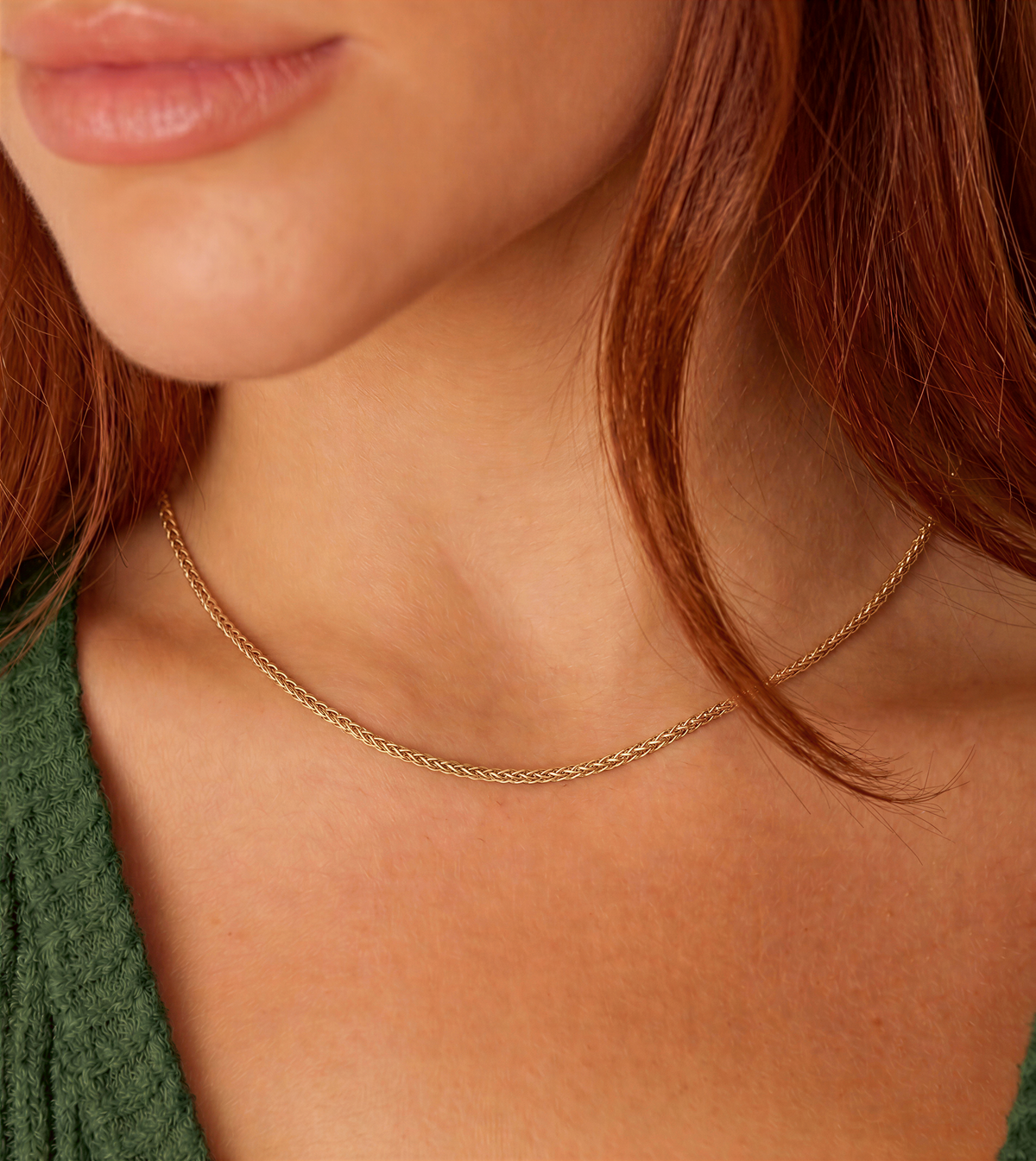 A close-up of a woman's neck and chest area, featuring a delicate gold chain necklace.
