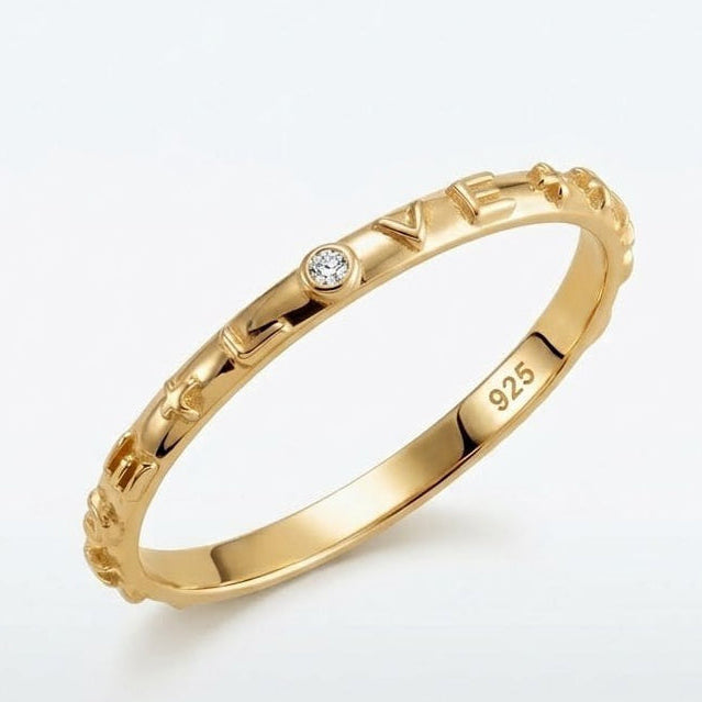Gold ring with 'LOVE' engraving and diamond on a white background