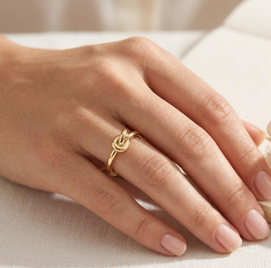 Hand wearing a gold-plated ring on a light background