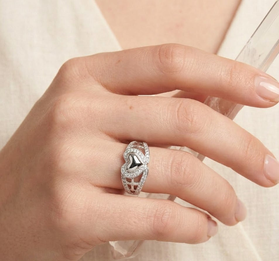 Hand wearing a silver ring with a black center on a light background