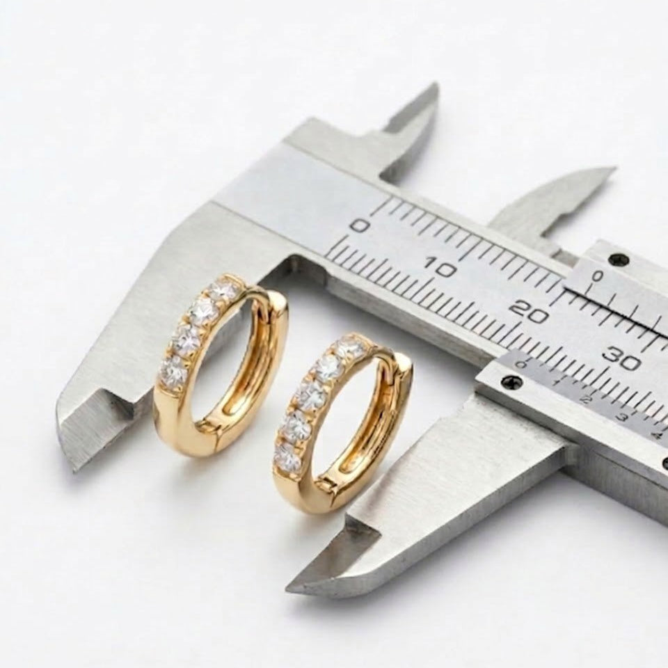 Hypoallergenic Diamond Alternative Huggie Earrings on a caliper against a white background