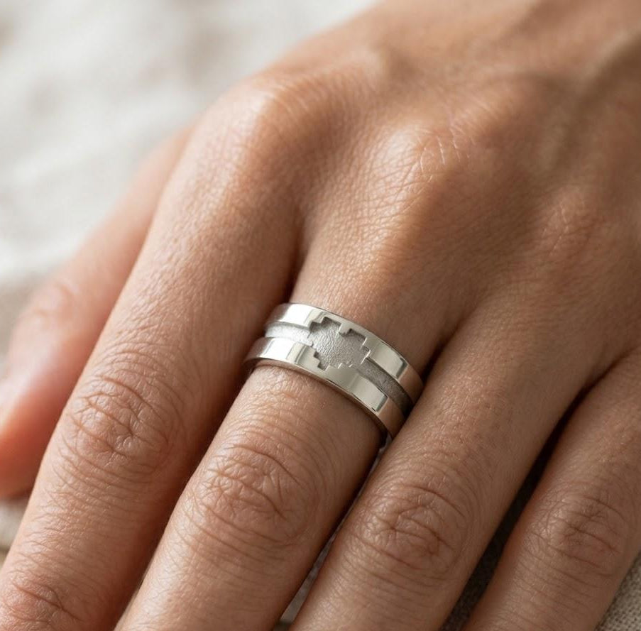 Silver ring on a person's finger with a neutral background