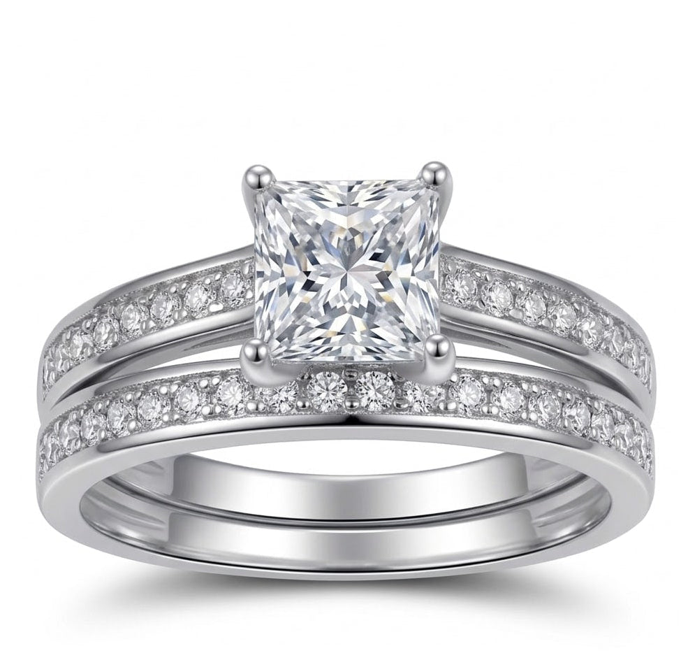 Silver ring with a large central moissanite and smaller moissanite on the band against a white background