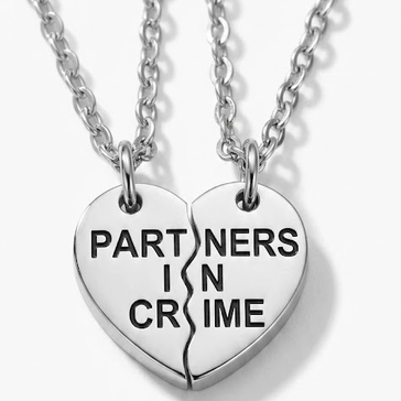 Two heart-shaped necklaces with 'Partners in Crime' engraved on a white background