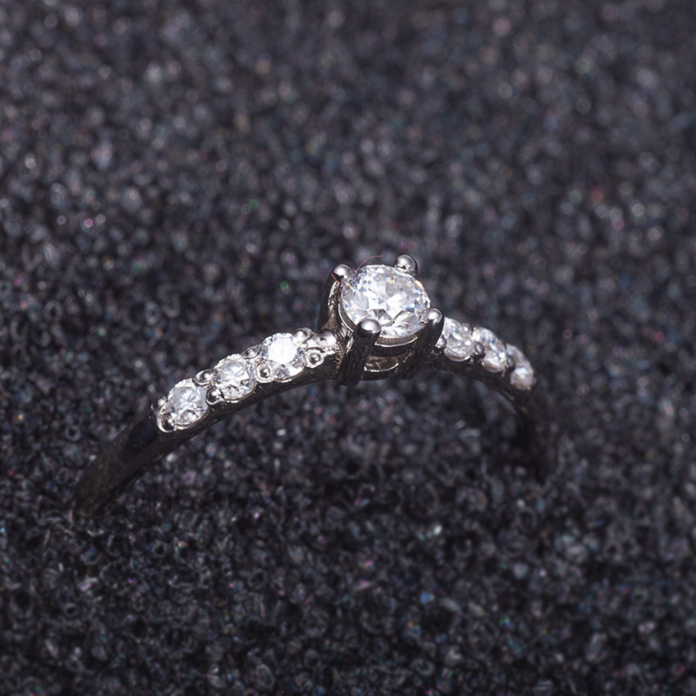 Dainty silver moissanite promise ring with 925 sterling silver band on black background side view