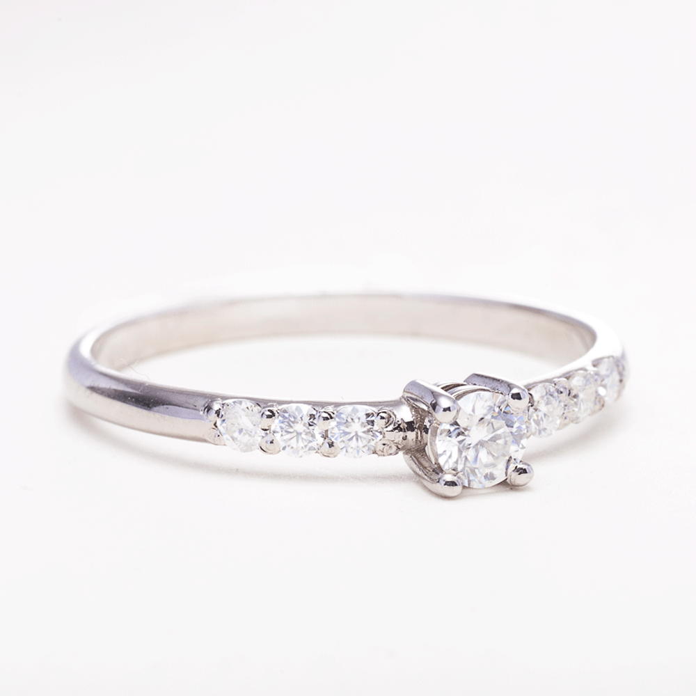 Dainty silver moissanite promise ring with 925 sterling silver band on white background side view