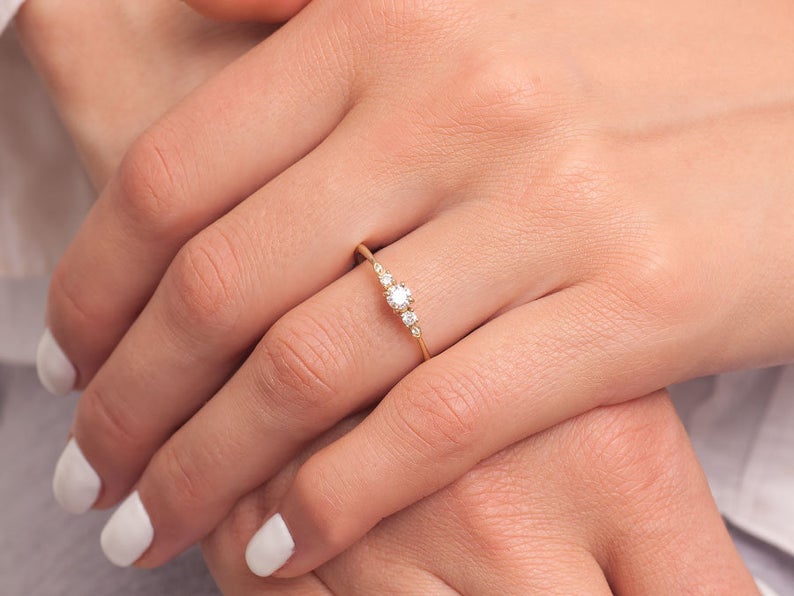 Promise ring for her worn on female hand with white nails