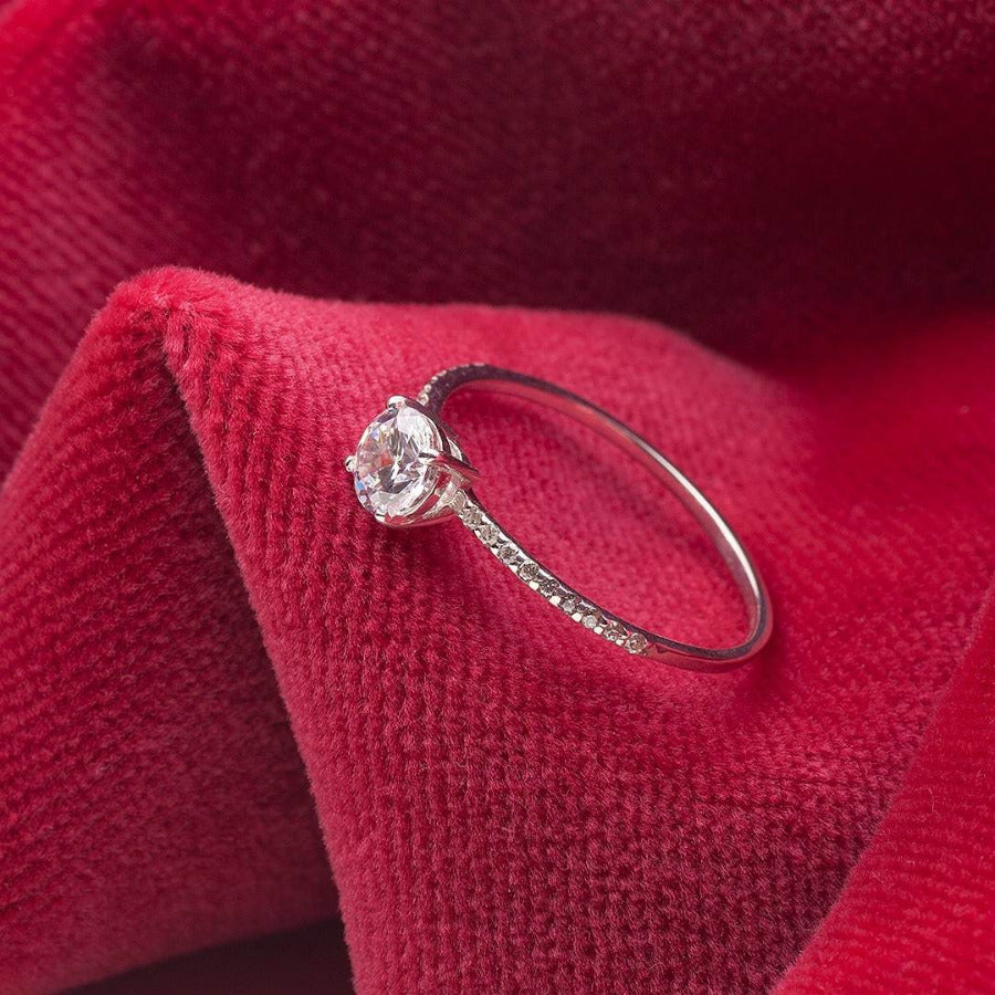 0,5 Carat Moissanite Engagement Ring in 14K white gold with 18 small diamonds on a thin band displayed on red fabric
