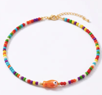 Colorful beaded necklace with an orange fish charm on a white background
