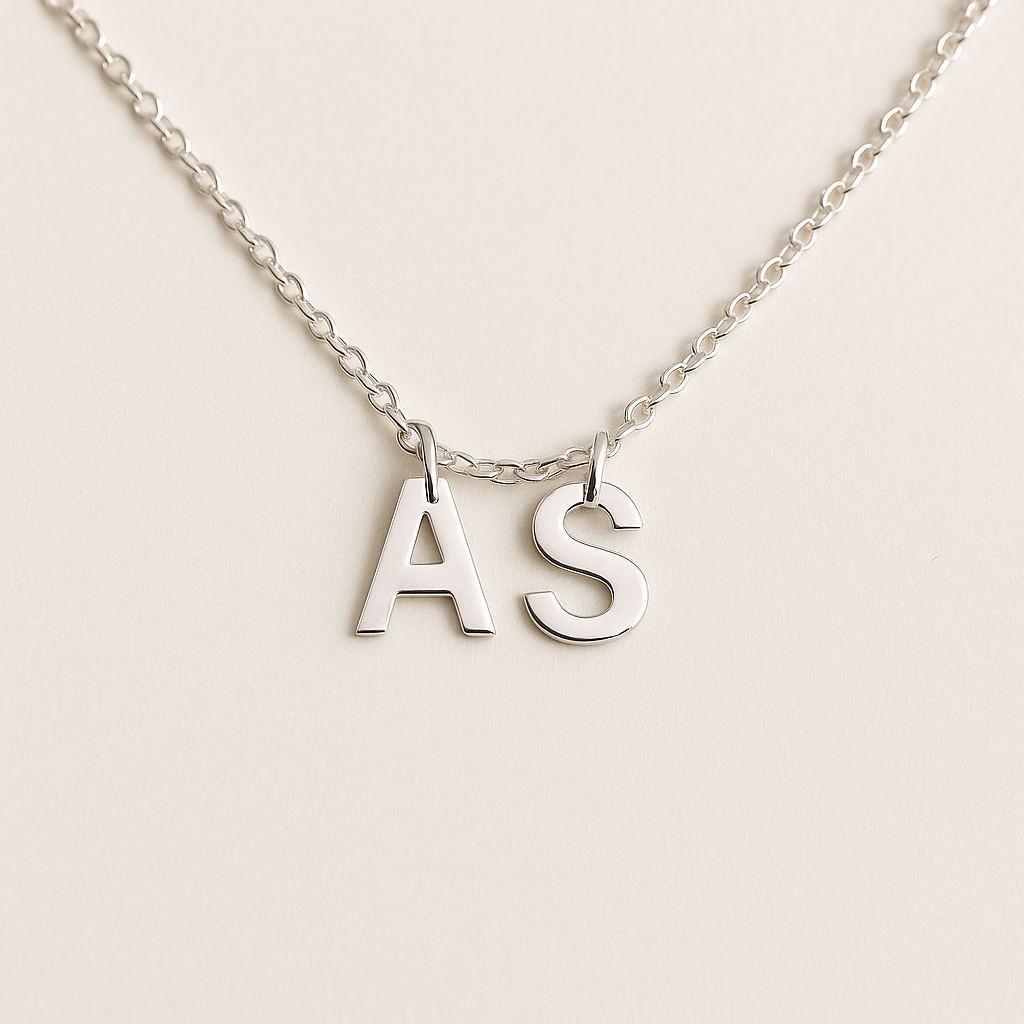 Silver necklace with 'AS' initials on a light beige background