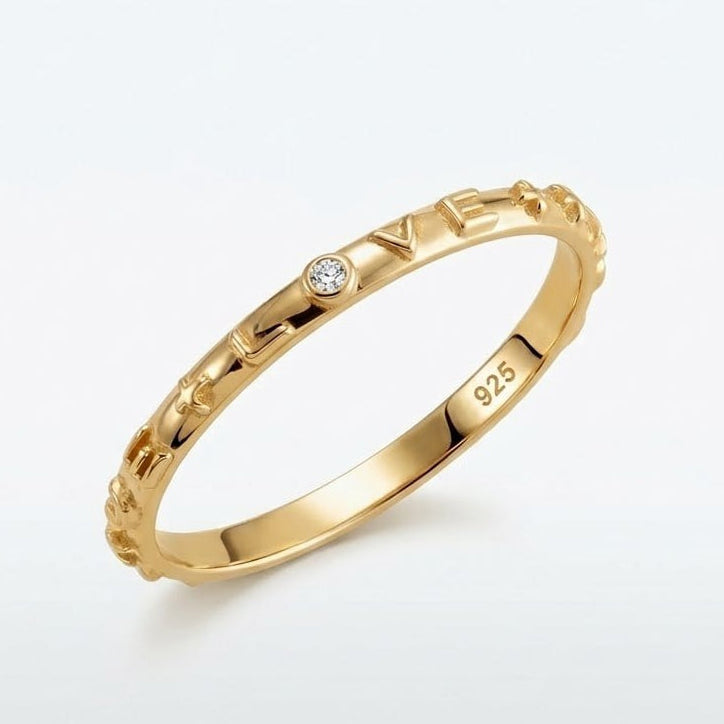 Gold ring with 'LOVE' engraving and diamond on a white background