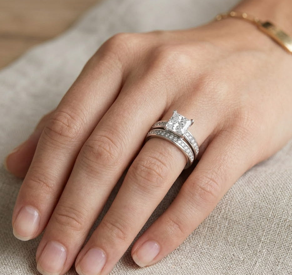 Hand wearing a silver ring with a moissanite on a textured fabric background