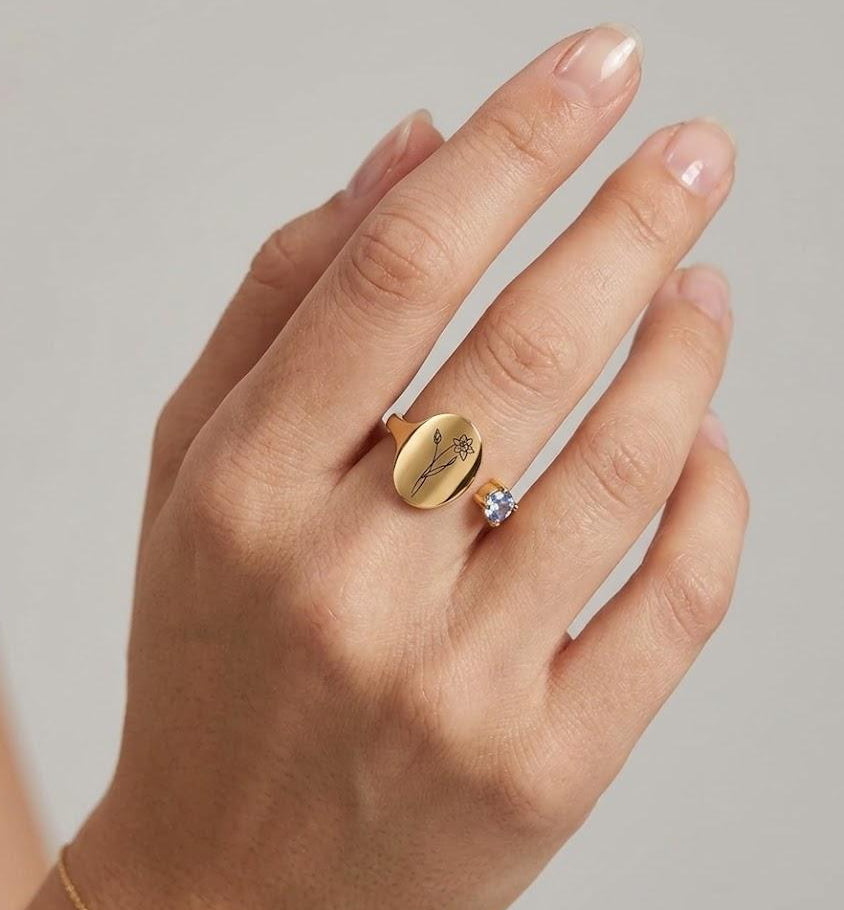 Modern minimalist birthflower ring on a woman's hand, gold and blue stone accent