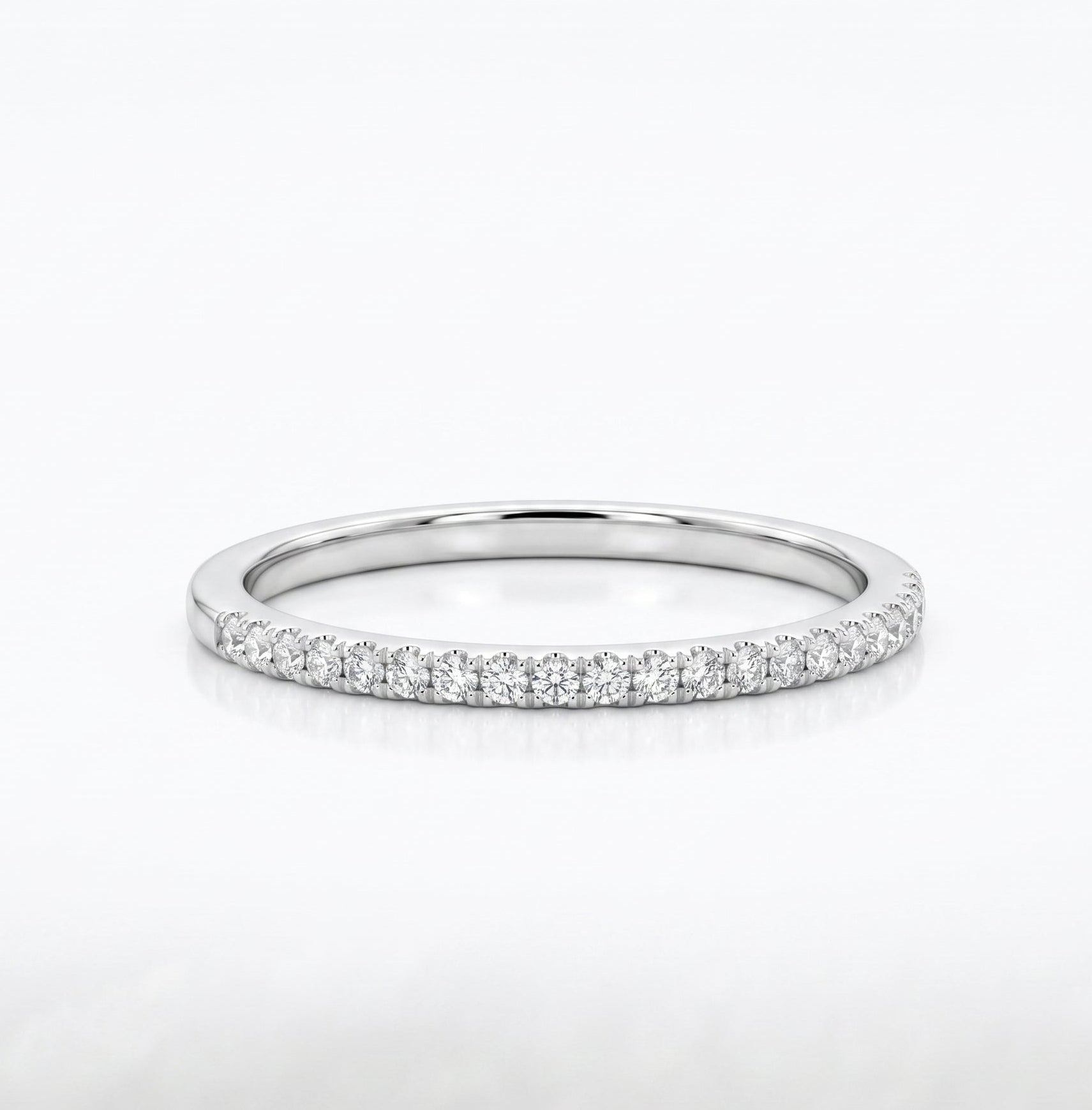 A thin silver band ring set with a row of small clear gemstones along the outer edge, photographed on a clean white background.