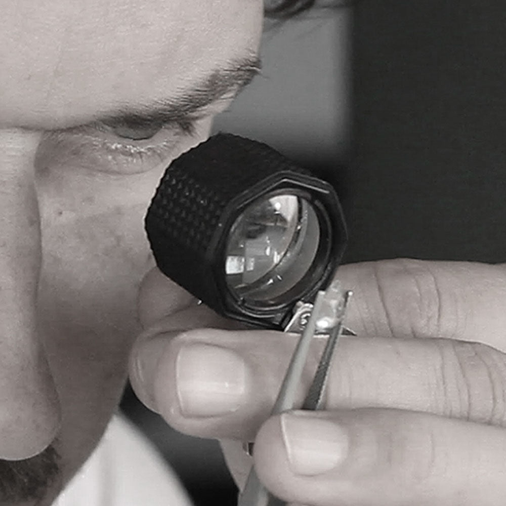Jeweler checking a gemstone with a loupe and tweezers before setting