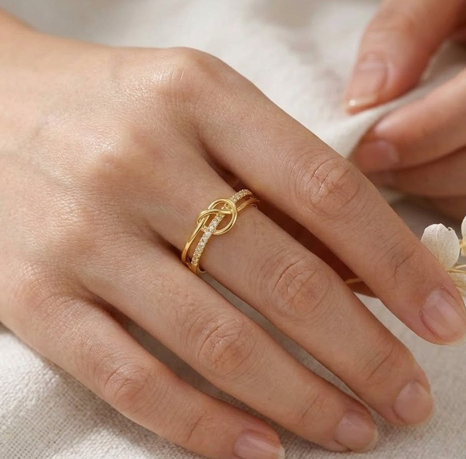 old Plated Silver Knot Purity Ring on a person's finger with a soft background