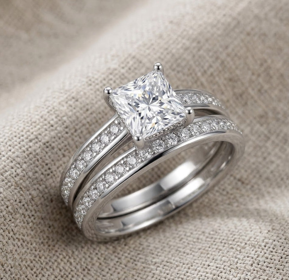 Silver ring with a large moissanite and a smaller moissanite on a textured beige background