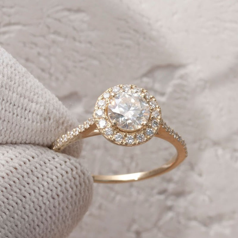 Close-up of 1-carat moissanite halo ring set in 14K yellow gold​  in finger
